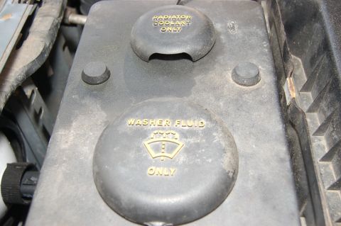 1989 Ford Bronco - Close-up of engine bay fluid reservoirs, one for radiator coolant and one for washer fluid.