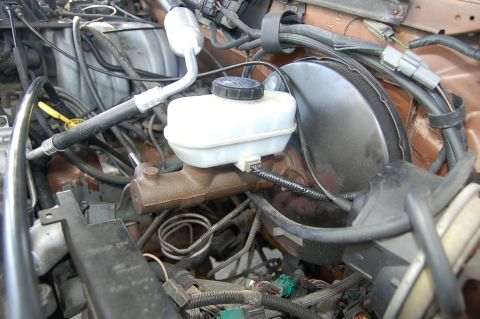 1989 Ford Bronco - Close-up view of the engine bay, focusing on the brake master cylinder and associated plumbing.