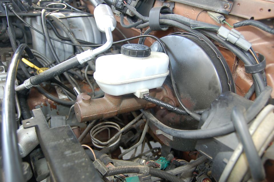 Engine bay showing brake master cylinder and various hoses and wires