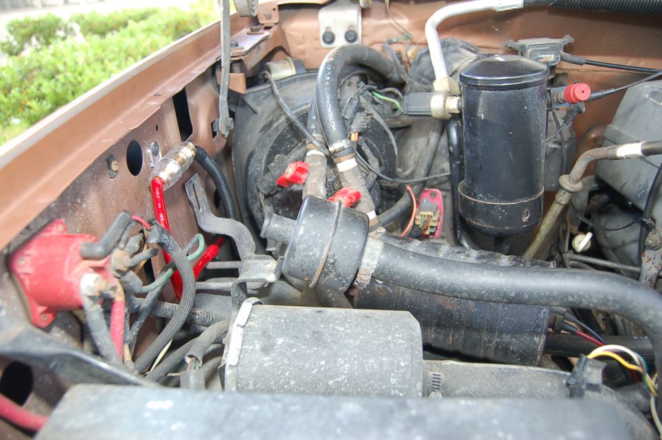 Engine bay with hoses, wires, and AC components visible