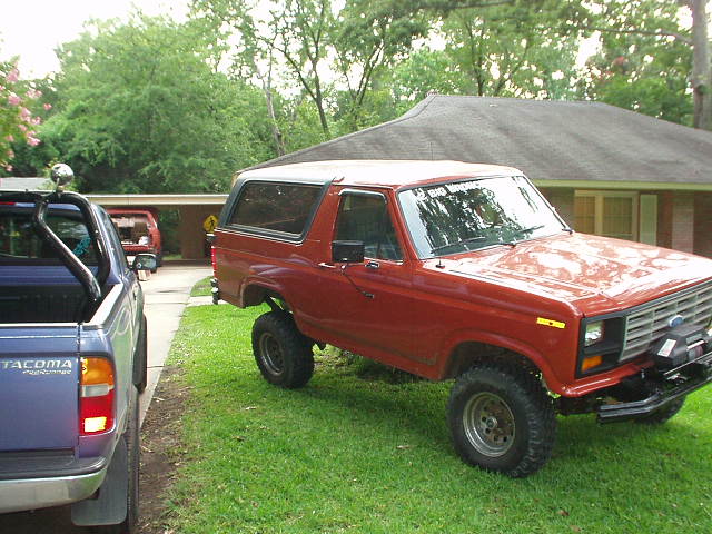 Red 1983 Ford Bronco parked on grass