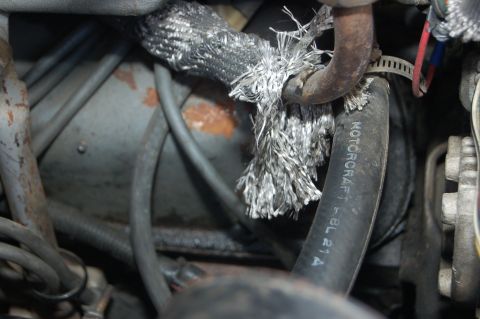 1989 Ford Bronco - Close-up of a damaged hose and wiring in a vehicle's engine compartment.