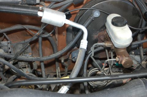1989 Ford Bronco - Close-up view of engine bay components including hoses and the brake fluid reservoir.