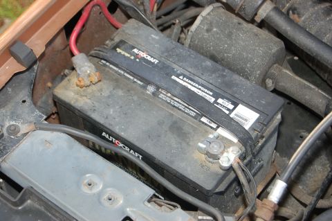 1989 Ford Bronco - Close-up of a car battery, likely in an engine bay, with visible text and warning labels.