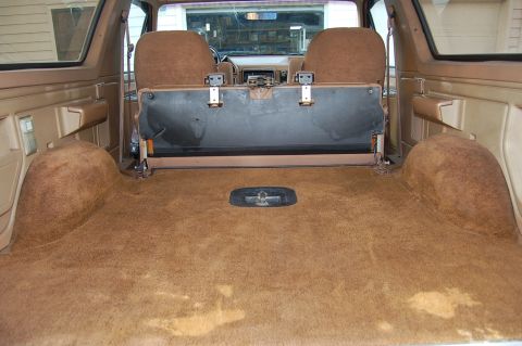 1989 Ford Bronco - The spacious cargo area of an SUV features plush brown carpeting and folding rear seats.