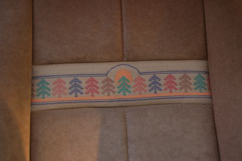 1989 Ford Bronco - Close-up of car seat fabric showing a decorative band with a sun and tree motif.
