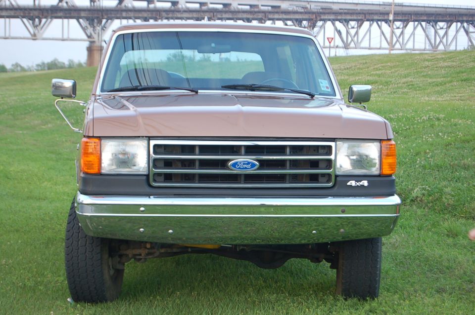 Front view of a brown 1989 Ford Bronco with a chrome grille and 4x4 badging