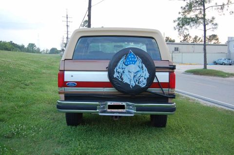 1989 Ford Bronco - This 1989 Ford Bronco is seen from the rear, a custom spare tire cover with a wolf and American flag graphic.