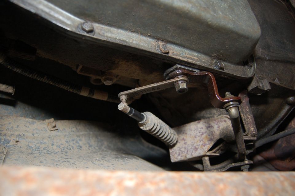 Transmission linkage with a spring and bracket attached to a metal casing