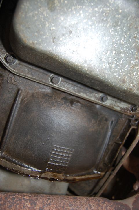 1989 Ford Bronco - Close-up view of a vehicle's transmission pan, showing signs of an oil leak and textured casting marks.