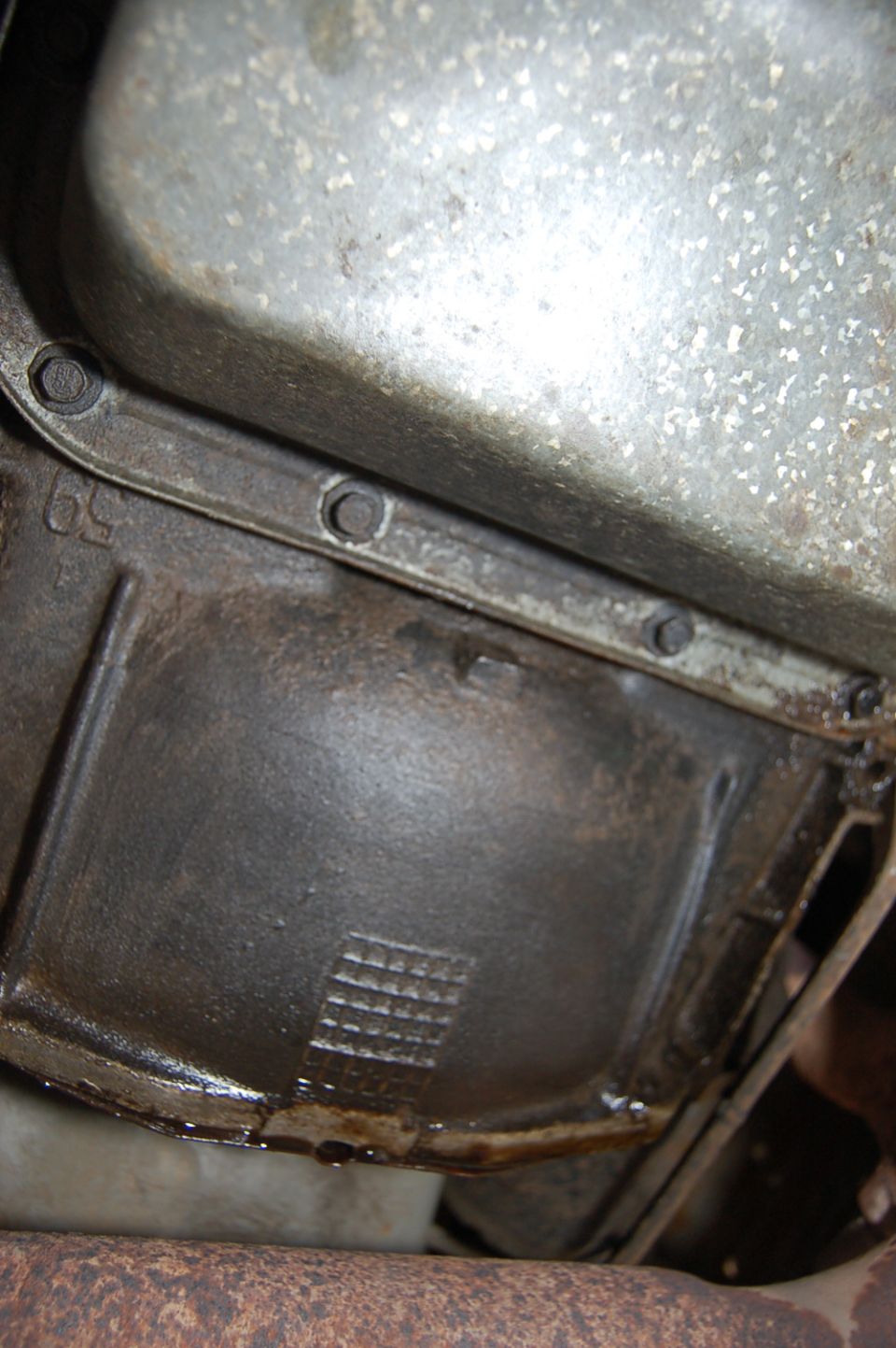 Transmission pan with visible oil leak and casting marks