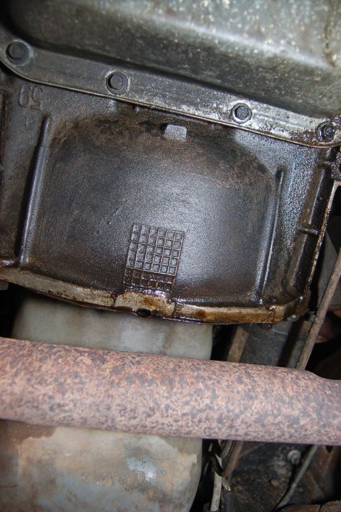 1989 Ford Bronco - Underside view of a vehicle's oil pan and exhaust pipe, showing signs of wear and tear.