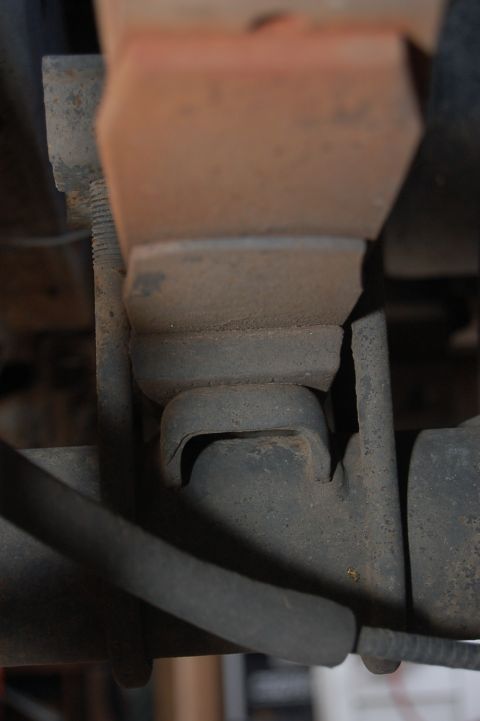 1989 Ford Bronco - This image shows a close-up view of a vehicle's suspension system, focusing on a rusty metal component and a rubber bushing.