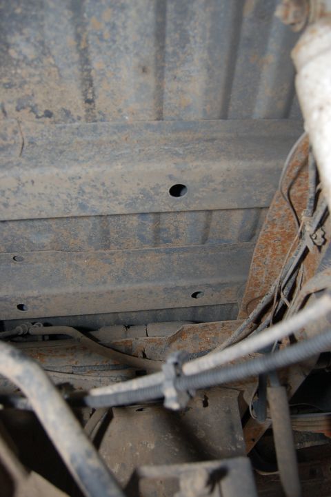 1989 Ford Bronco - Undercarriage view showing the frame and suspension of a vehicle, with visible rust and wiring.