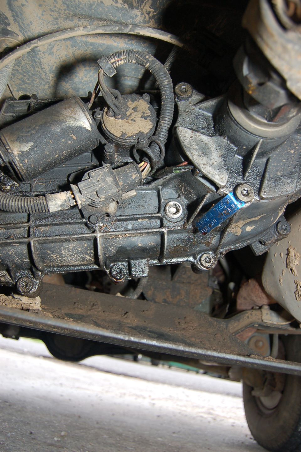 Underside view of a vehicle's transmission and transfer case with some blue tape on it