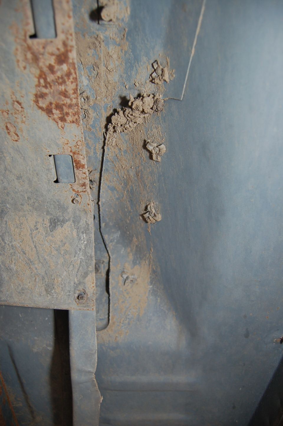 Close-up of rusty metal and dirt on a vehicle's undercarriage