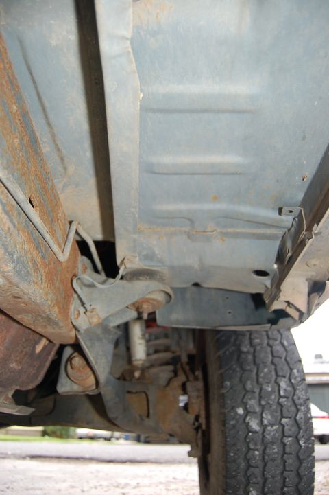 1989 Ford Bronco - The underside of a vehicle reveals rusted metal and suspension parts, with a tire visible.