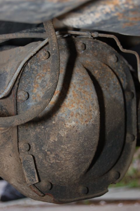 1989 Ford Bronco - Close-up view of a rusty rear differential assembly, showing its bolted cover and brake lines.