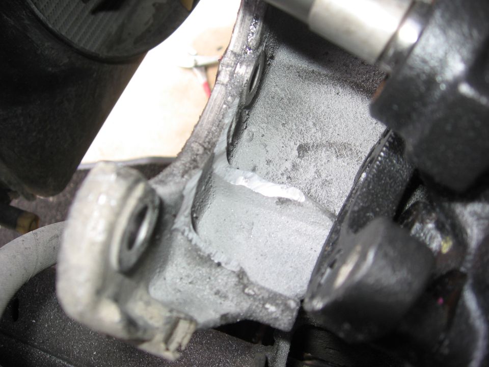 Close-up of a power steering pump bracket with visible wear and repair marks