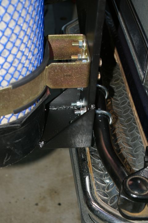 1986 Ford Bronco - Close-up view of a rear bumper assembly, including a tow hitch and a blue mesh object, with visible mounting hardware.