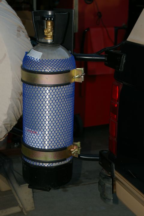 1986 Ford Bronco - A propane tank is secured to the exterior of a vehicle, likely for auxiliary power or equipment.