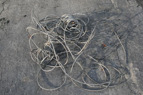 2003 Jeep TJ - A pile of tangled gray cables rests on a weathered asphalt surface.