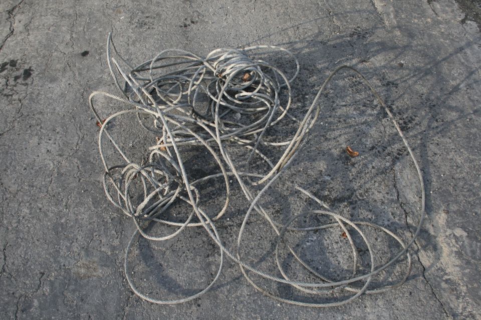 Tangled gray cables lie coiled on cracked asphalt