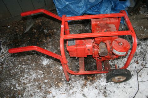 2003 Jeep TJ - A red generator with wheels and handles sits on the ground, partially covered in snow.