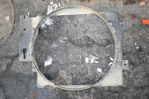 2003 Jeep TJ - A radiator fan shroud, likely for a Jeep TJ, is shown lying on asphalt. It features a large circular opening and several mounting points.