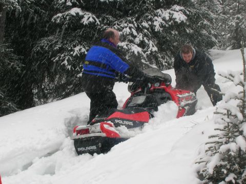 2003 Jeep TJ - Two men work to free a Polaris snowmobile stuck in deep snow during a snowfall.