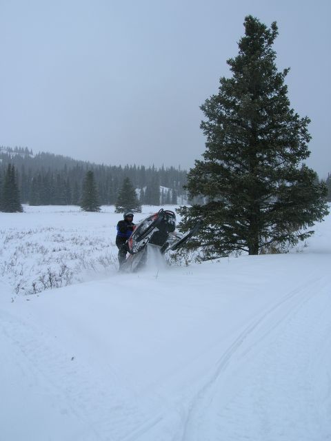 2003 Jeep TJ - A snowmobile is tipped on its side in a snowy landscape, with a person standing nearby.