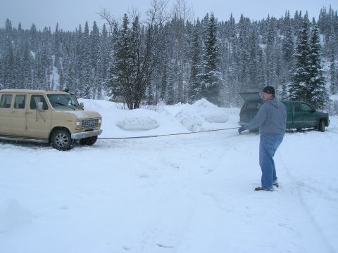 2003 Jeep TJ - Two vehicles are stuck in the snow, with a man standing between them.