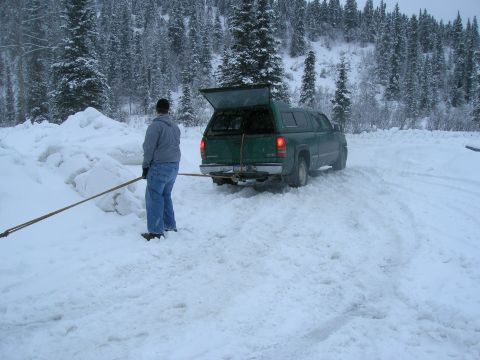 2003 Jeep TJ - A person stands in the snow next to a green pickup truck with its cap open.