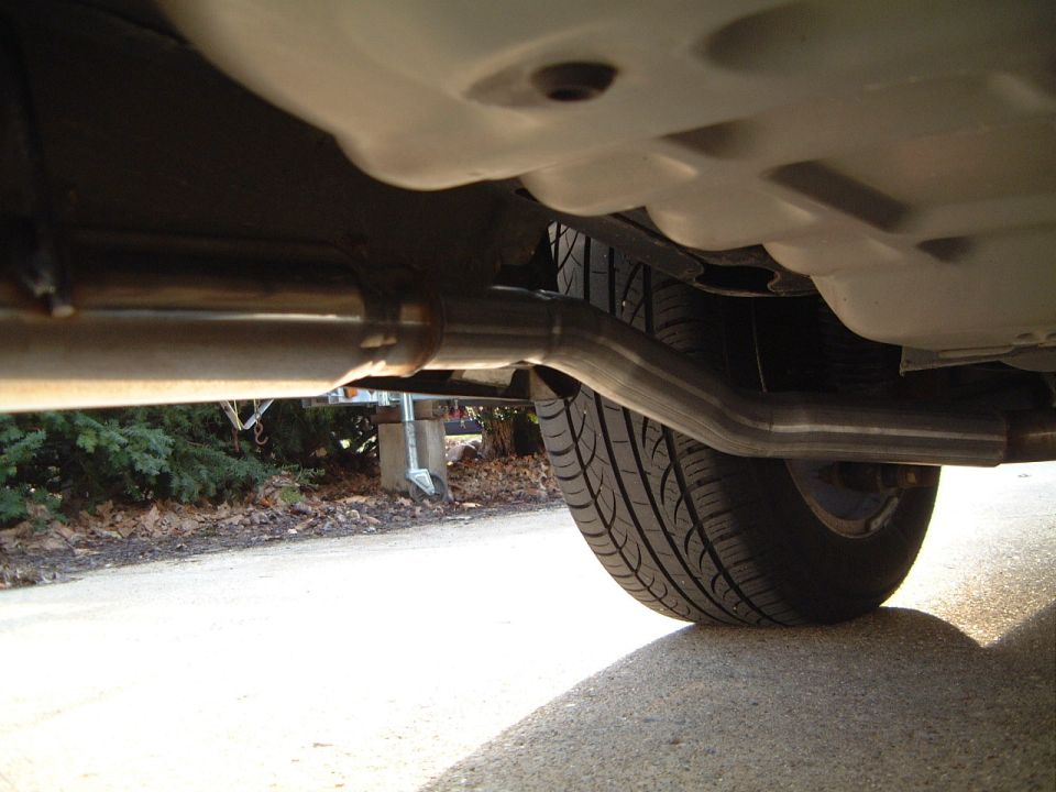 Underbody view of a car showing exhaust pipe and rear tire