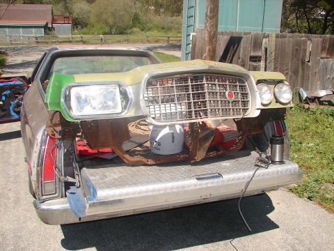 1973 Ford Ranchero - Front clip of a 1970s Ford Ranchero loaded nose-first into a pickup bed with a diamond-plate tailgate, showing the wide egg-crate grille, r…