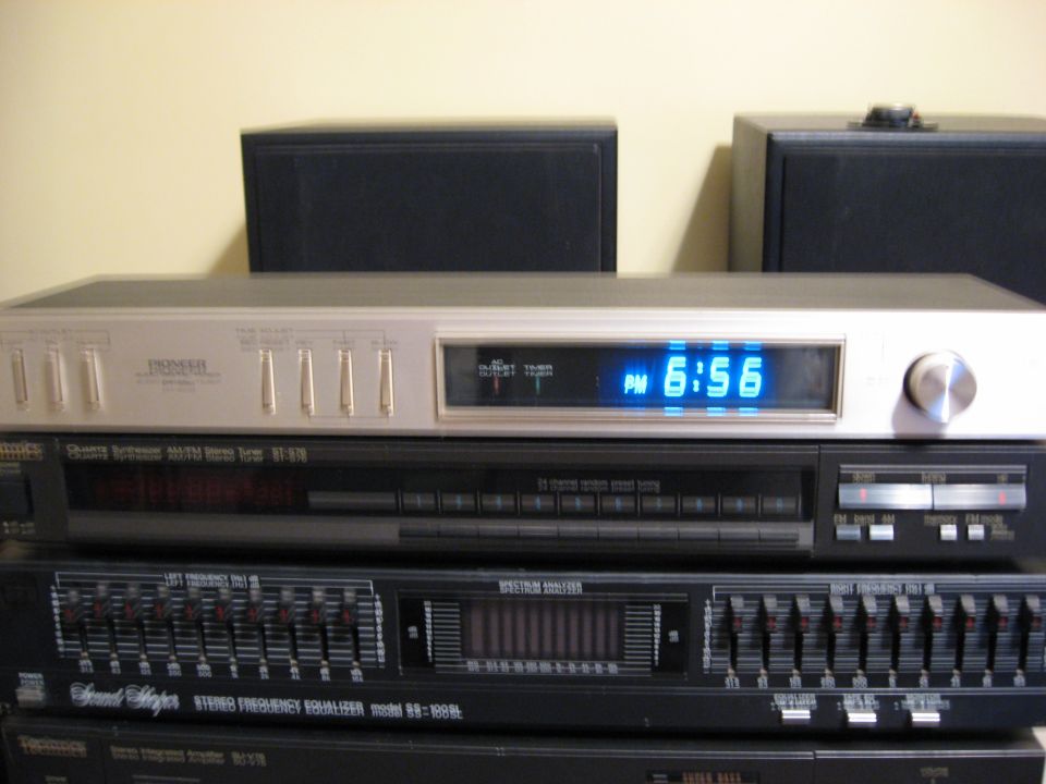 Pioneer stereo tuner with blue digital clock showing 6:56 PM, stacked on other audio equipment