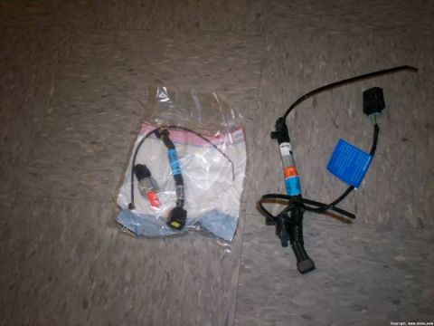 2007 Ford Mustang - Two automotive wiring harnesses are shown on a floor. One is in a plastic bag.