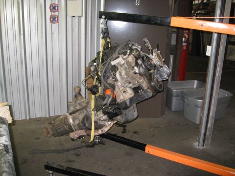 1994 Jeep YJ - Engine and transmission assembly being lifted by an engine hoist in a workshop.