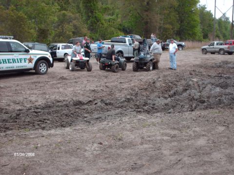 1982 Ford F-100 - A sheriff's patrol car and multiple ATVs are gathered in a muddy, outdoor area, with several people present.