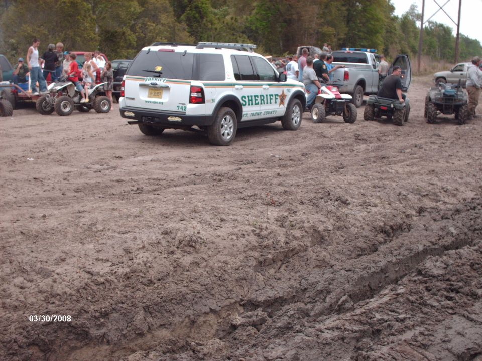 Sheriff's SUV parked in mud with ATVs and people around
