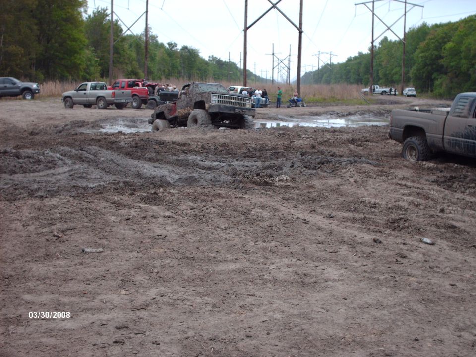Trucks stuck in a mud pit with power lines overhead. Date stamp 03/30/2008