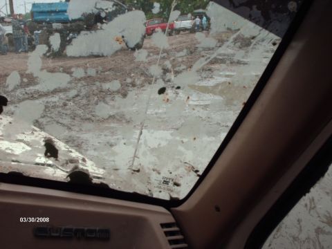 1982 Ford F-100 - View from inside a truck with a muddy windshield shows other vehicles in a muddy outdoor scene.