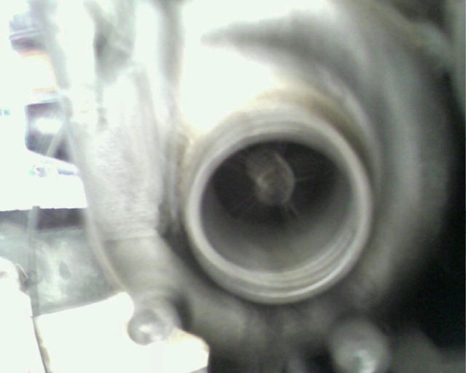 Close-up looking into a turbocharger inlet with visible turbine wheel