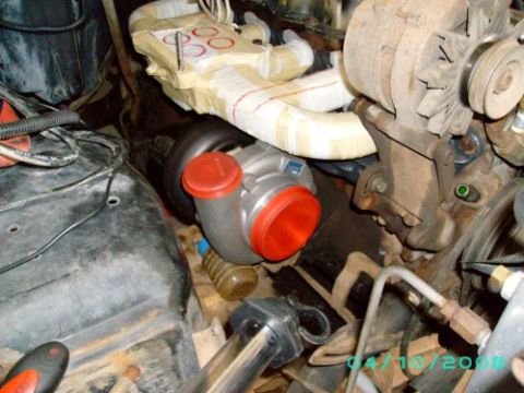1979 Ford F-150 - Close-up view of a turbocharger being installed in an engine bay, with various engine components visible.