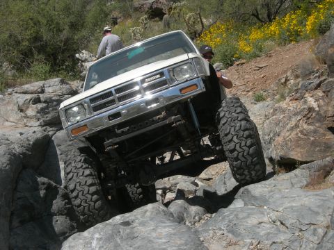 1974 Ford F-250 - A modified Toyota pickup navigates a rocky trail with steep inclines and sparse vegetation.