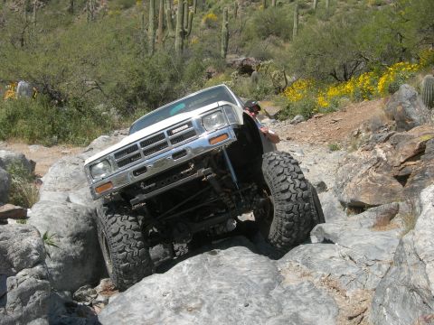 1974 Ford F-250 - A modified Toyota pickup truck tackles a challenging rocky trail in a desert landscape.