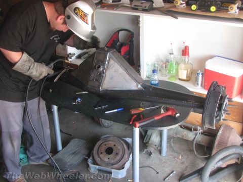 1968 Ford Mustang - A person in a welding mask and gloves works on a custom-fabricated differential housing, with tools and parts scattered around.
