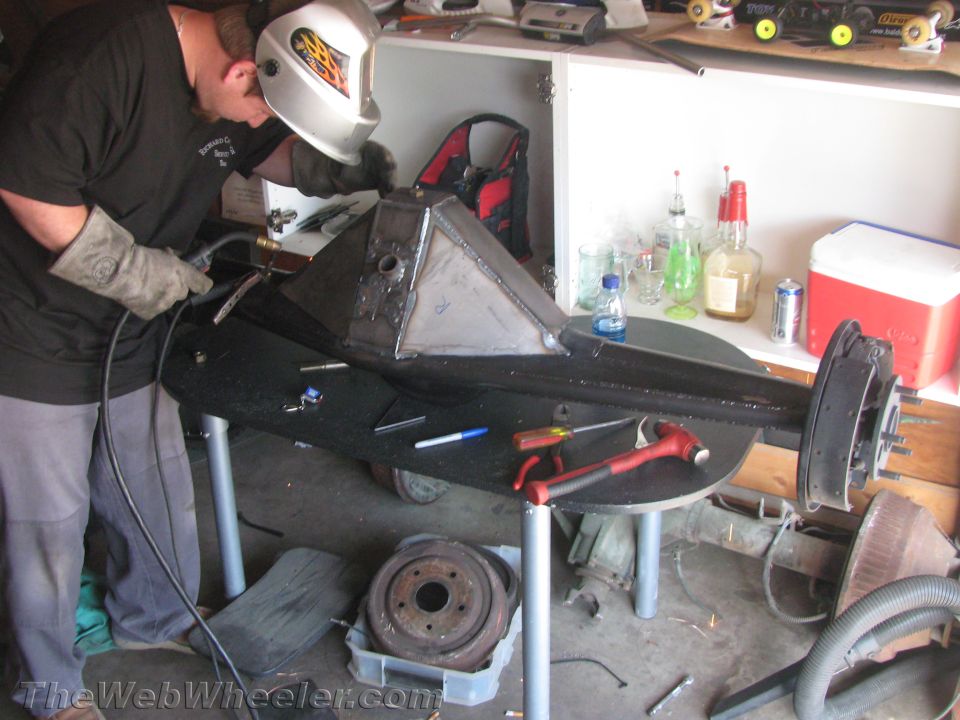 Welder fabricating a custom differential housing on a workbench