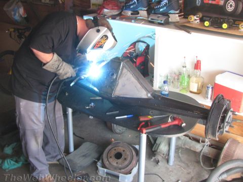 1968 Ford Mustang - A person is welding a fabricated metal part in a workshop setting.