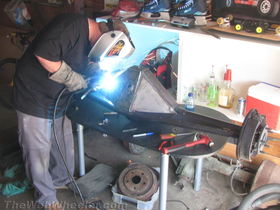 Man in welding mask and gloves working on a metal component on a table